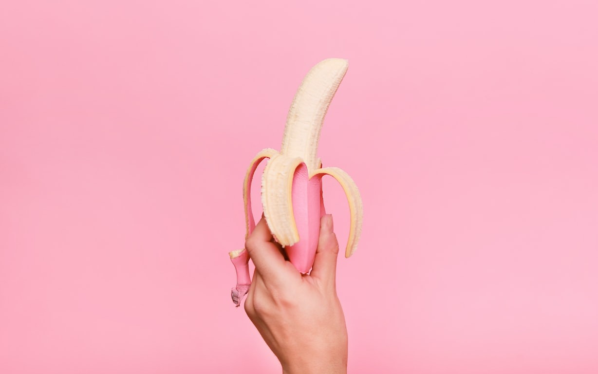 person holding a banana on pink backdrop