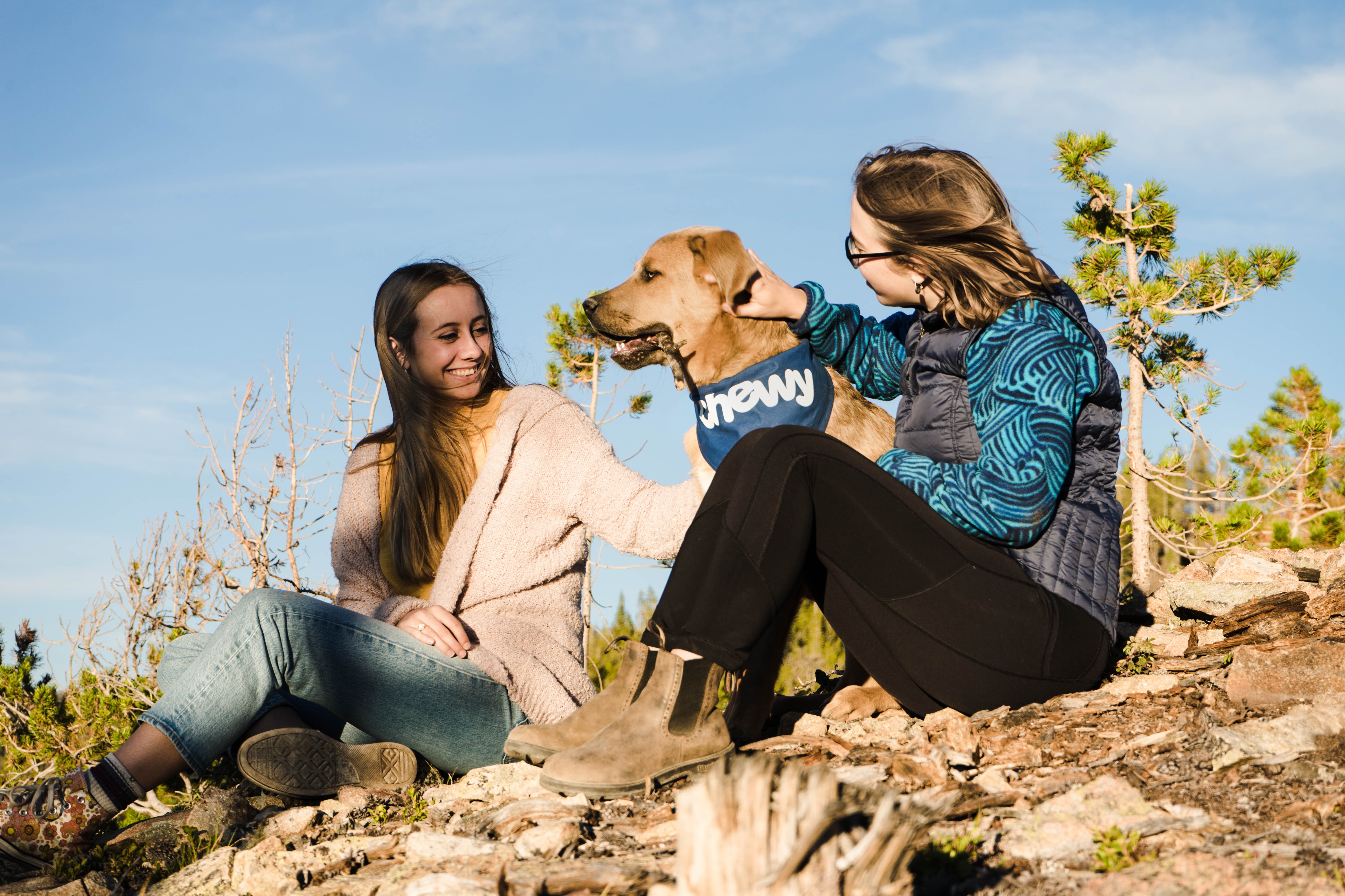 two women and a dog on a rocky surface