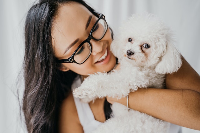 woman holding a white poodle dog