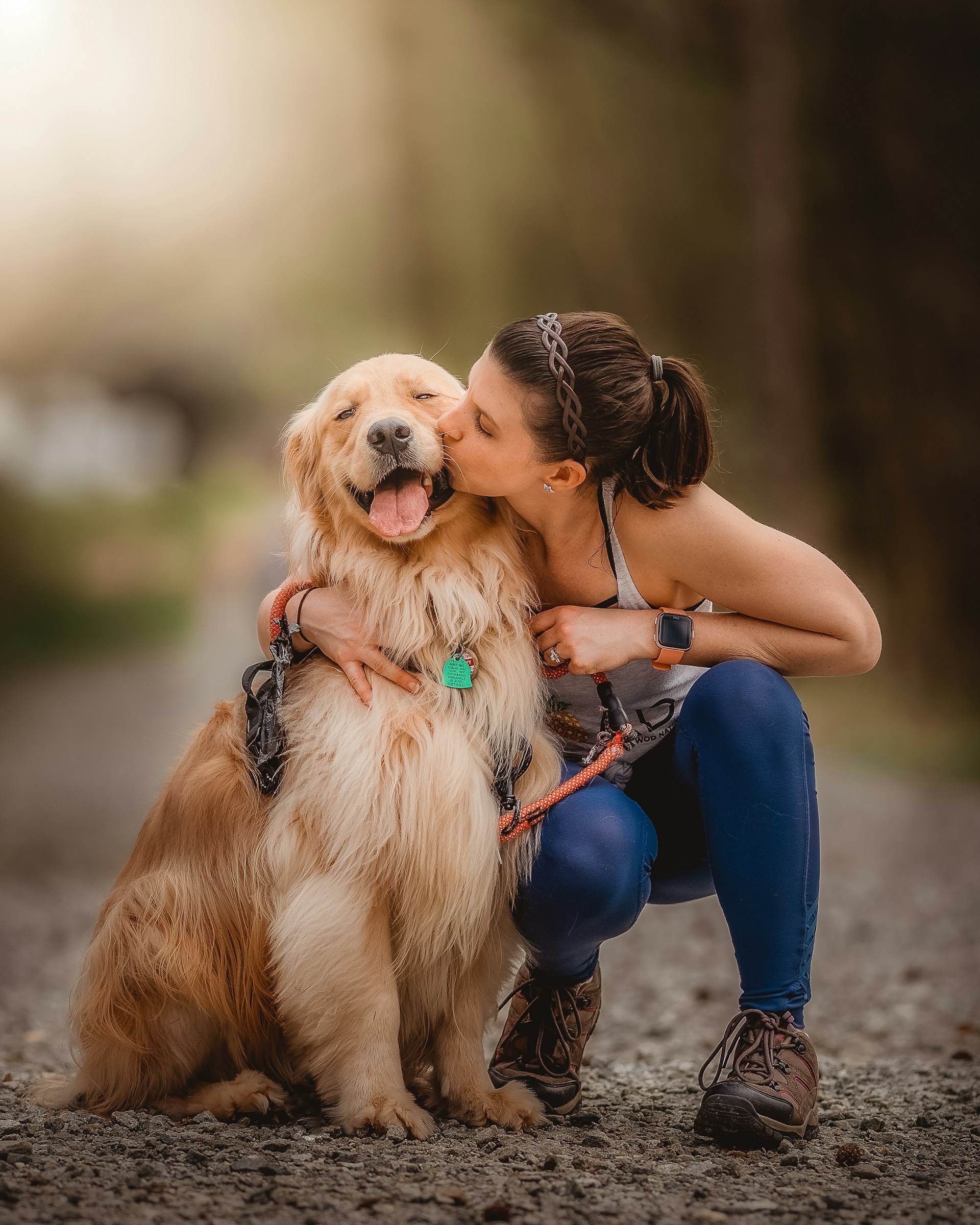 a woman kissing an adult dog outdoors